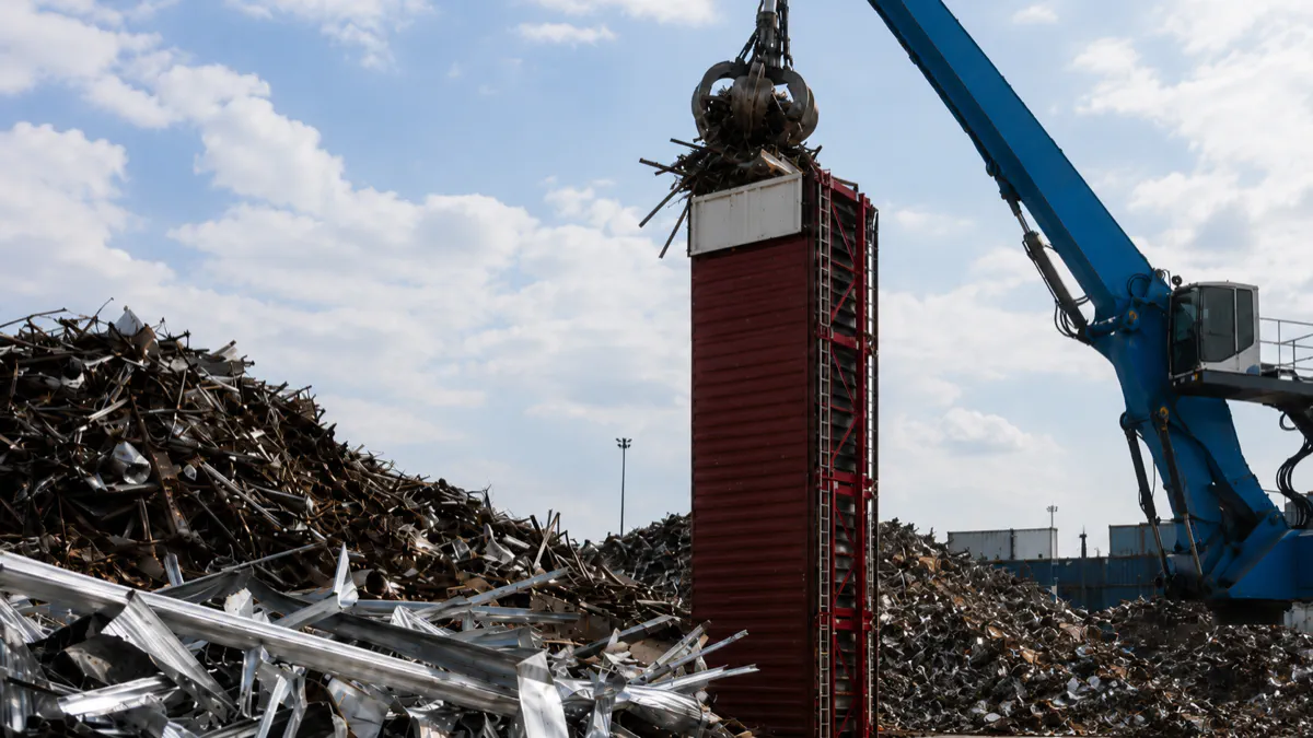 Vertical loading of scrap metal and aluminium into an upright ISO container at a recycling facility